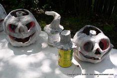 three halloween pumpkins made out of cans sitting on top of a white table outside