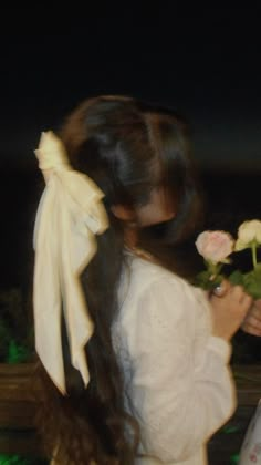 a girl with long hair holding flowers in her hand