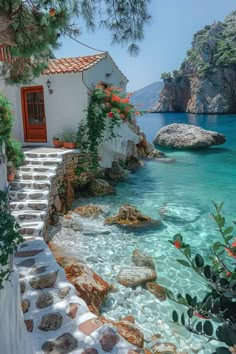 a house on the shore with steps leading to it and flowers growing out of the water