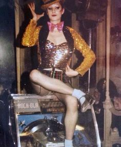 a woman is posing on top of a motorbike in a sequined outfit