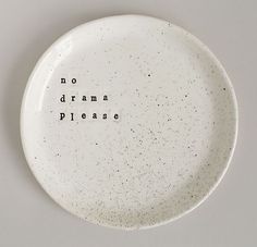 a white plate with the words no drama please written on it and black speckles