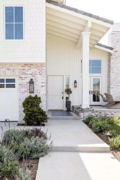 the front entrance to a home with white doors and brick pillars on either side of the house