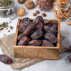 a wooden bowl filled with raisins on top of a table next to nuts