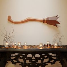 a table topped with candles and vases filled with small white flowers next to a wooden arrow