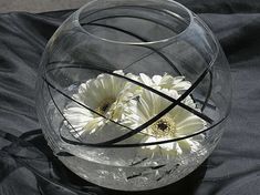 two white flowers in a clear glass vase on a black cloth covered tablecloth,