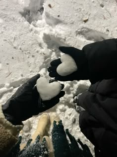 two people are standing in the snow with their hands out to touch each other's fingers