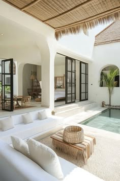 a living room with white couches and tables next to a swimming pool in the middle of it