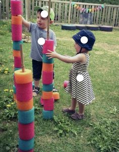 two young children playing with colored blocks in the yard, one has his hand on the pole