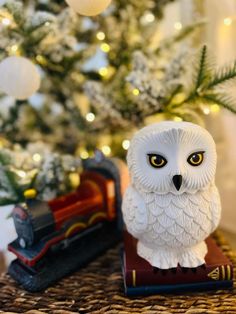 an owl figurine sitting on top of a book next to a christmas tree