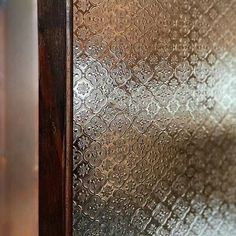 a close up view of a metal door with an intricate design on the glass and wood frame