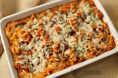 a casserole dish with cheese and vegetables in it sitting on a tablecloth