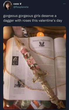 an open book with flowers on it next to a candle and a chain that is attached to the book