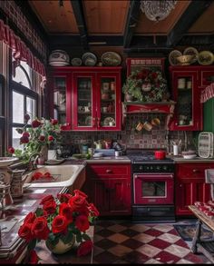 a kitchen with red cabinets and checkered flooring on the walls is decorated for christmas