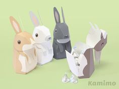 three paper rabbits sitting next to each other on top of a green surface with candy