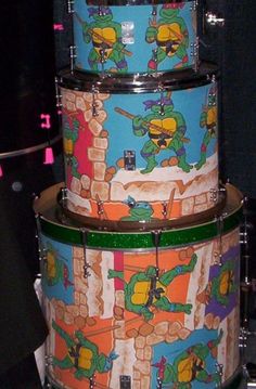 three drum sets with teenage mutant designs on them, all stacked up and ready to be played