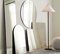 a large mirror sitting on top of a floor next to a lamp