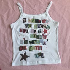 a white tank top with words written in different languages and stars on the chest,