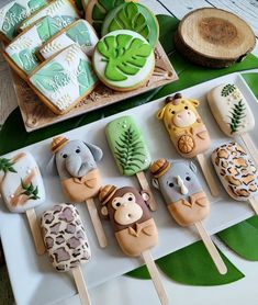 there are many decorated cookies on the table with green leaves and trees around them, including giraffes