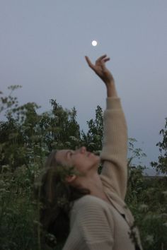 a woman reaching up into the air to catch a frisbee in her hand