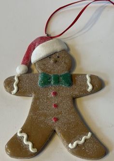 an ornament shaped like a gingerbread man wearing a santa hat and bow tie