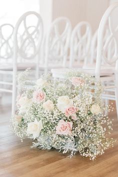 a bouquet of flowers sitting on top of a wooden floor next to white rocking chairs