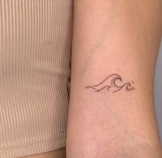 a woman's arm with a small wave tattoo on it