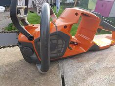 an orange chainsaw sitting on top of a wooden table