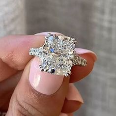 a woman's hand holding an engagement ring with two diamonds on the top and bottom