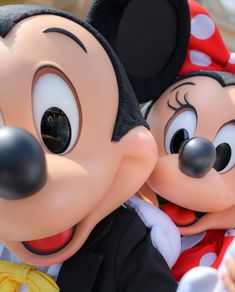 two mickey and minnie mouse heads in front of each other