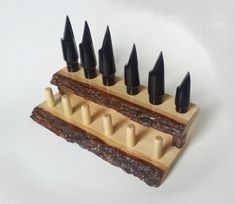 a wooden holder with black spikes on it's sides and four rows of nails sticking out of the top