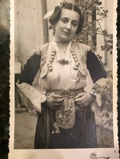 an old black and white photo of a woman in traditional dress with flowers on her head