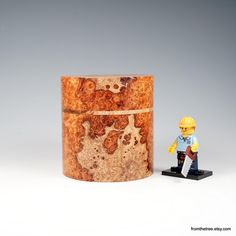 a lego man standing next to a wooden container