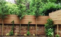 a wooden fence with plants growing on the sides and in between it is a brick wall