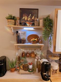 a kitchen area with coffee maker, potted plants and other items on the shelves