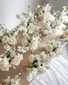 white flowers and greenery are arranged on a table