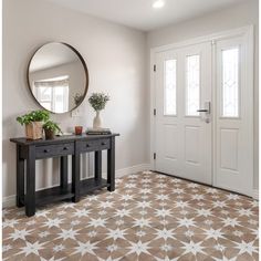 a foyer with a mirror, table and potted plants