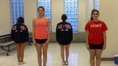 four girls in red and black shirts standing next to each other with their backs turned