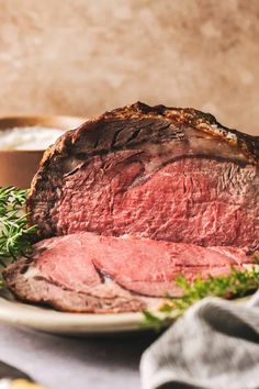 a piece of roast beef on a plate with parsley next to it and a bowl in the background