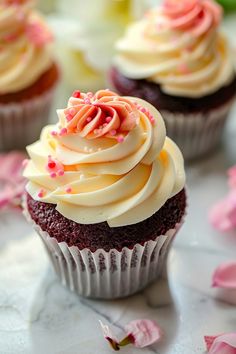 cupcakes with white frosting and pink sprinkles on a table