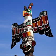 a totema statue on top of a wooden pole in front of a blue sky