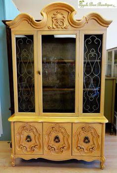 an antique china cabinet with glass doors and carvings on the front, painted in yellow