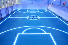 an indoor basketball court is lit up with blue lights and white lines on the floor