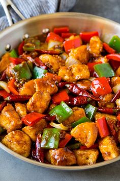 a pan filled with chicken and peppers on top of a table next to a fork