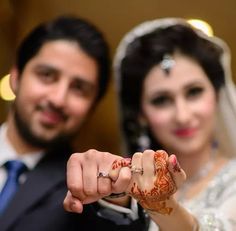 a man and woman holding hands with henna on their fingers, posing for the camera