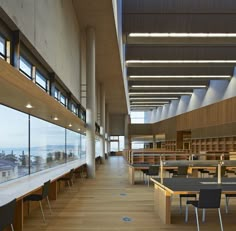 an empty library with tables and chairs overlooking the ocean from it's high ceilings