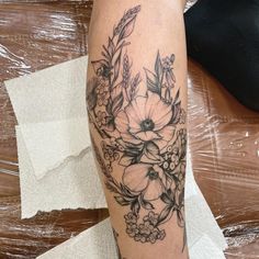 a woman's leg with flowers and leaves on it