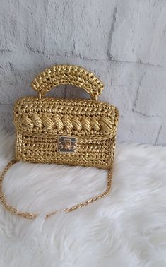 a gold handbag sitting on top of a white furnishce covered floor next to a brick wall