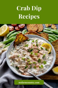 a white bowl filled with crab dip next to crackers and green beans