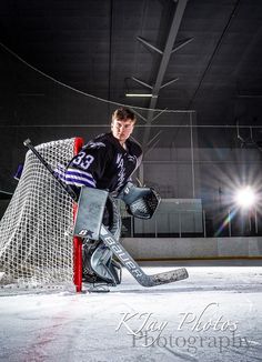 a young man playing hockey on an ice rink in front of a goalie net