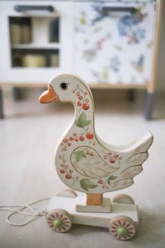 a wooden duck on wheels with cherries painted on it